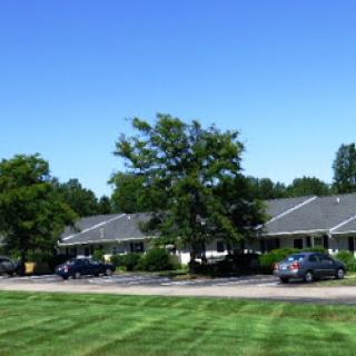 A serene view of a building surrounded by greenery and clear blue skies.