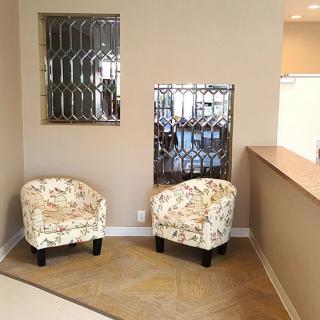 A cozy seating area with two patterned chairs and decorative mirrors on the wall.