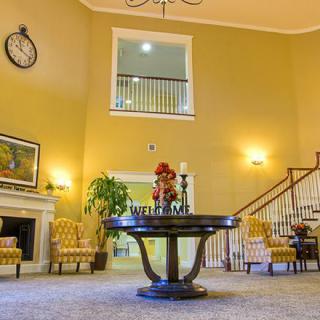 A spacious lobby with elegant decor, featuring a central table and a staircase.