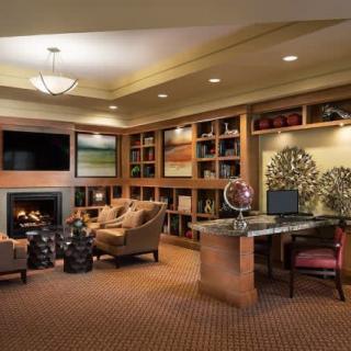 A cozy living room featuring a fireplace, bookshelves, and a home office setup.