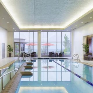 A luxurious indoor swimming pool with modern design and relaxation areas by large windows.