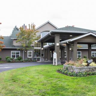 A well-maintained building entrance with landscaped lawns and trees.