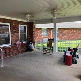 A cozy outdoor porch space featuring a rocking chair and ceiling fans, perfect for relaxation.