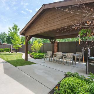 A cozy backyard patio with a pergola and outdoor seating surrounded by lush landscaping.