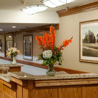 A cozy hotel lobby with a reception desk adorned by vibrant floral arrangements and framed artwork on the walls.