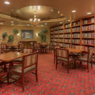 An elegant library with tables and chairs surrounded by shelves filled with books.