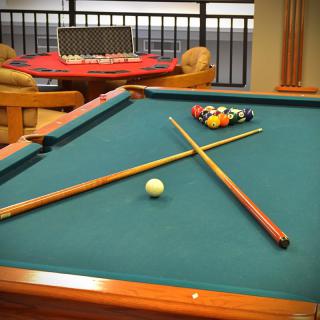 A billiards table set for a game with cue sticks and balls in a cozy game room.