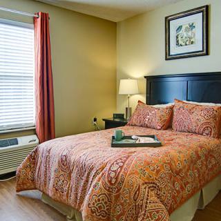 A cozy bedroom with a neatly made bed and warm lighting.