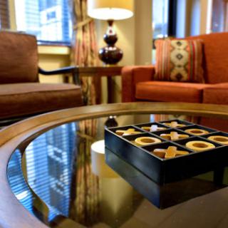 A cozy hotel lounge featuring comfortable seating and a box of assorted chocolates on the table.