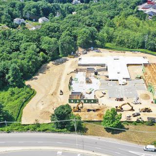 An aerial view of a construction site surrounded by greenery, showcasing ongoing land development.