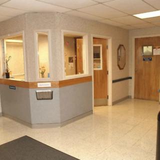 The image shows a hospital reception area with a front desk and doors leading to other rooms.