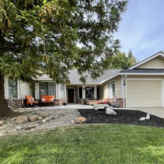 A welcoming residential home with a landscaped front yard and patio seating.