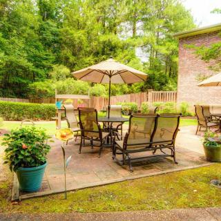A cozy backyard patio with seating and an umbrella, surrounded by greenery.