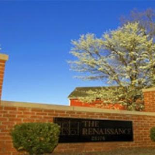 A scenic view showing a sign for The Renaissance, surrounded by greenery and a clear blue sky.