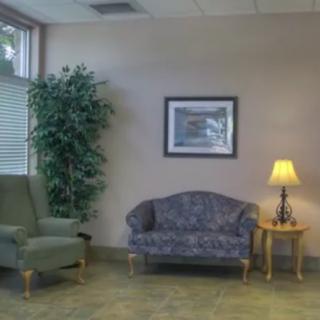 A cozy waiting room with a sofa, armchair, and a side table with a lamp.