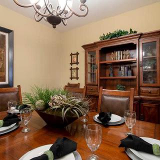 A cozy dining room with a wooden table set for guests, featuring elegant place settings and a classic chandelier.