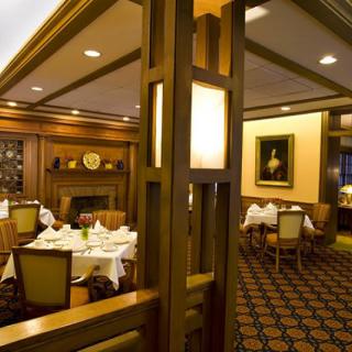 A warmly lit restaurant interior with elegantly set tables and comfortable seating.