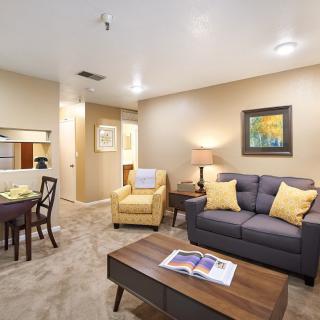 A cozy living room with modern furniture, including a sofa, armchair, coffee table, and dining area.
