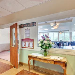 A cozy lobby area featuring a flower arrangement on a wooden table, welcoming visitors with an inviting atmosphere.