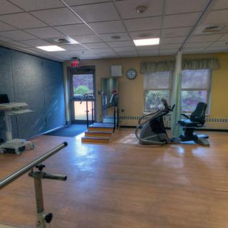 A well-lit gym room featuring various exercise equipment, including a treadmill and a stationary bike.