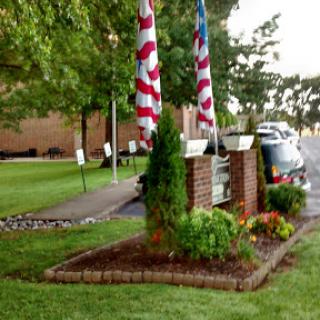 A well-maintained garden area featuring American flags in front of a building.