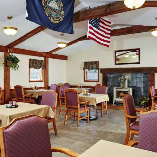 A cozy dining room with flags hanging from the ceiling and neatly arranged tables and chairs.