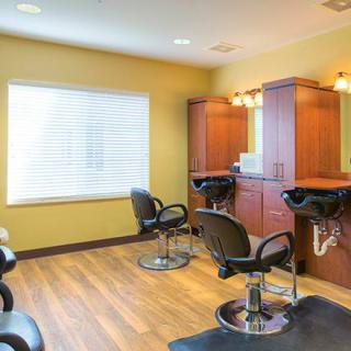 Interior of an empty hair salon with chairs, mirrors, and wooden flooring.