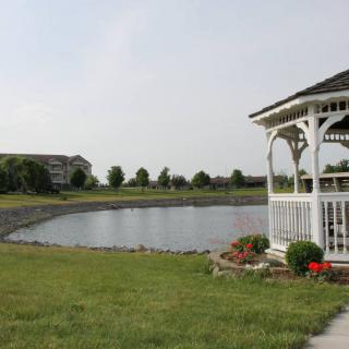 A scenic view of a gazebo overlooking a pond in a park setting.