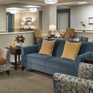 A cozy living room with a blue sofa and patterned armchairs, complemented by soft lighting and decorative accents.