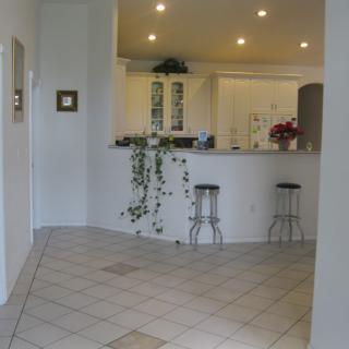 A modern kitchen interior featuring a counter with stools and decorative plants.