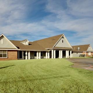 A suburban house with a large lawn under a partly cloudy sky.