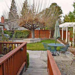 A cozy backyard with a patio, garden furniture, and a grassy area surrounded by trees.