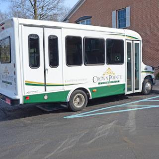 A white and green bus parked in a lot, ready for passengers.