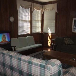A cozy living room with multiple sofas, a television, and wood-paneled walls.