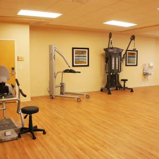 A clean and spacious exercise room with fitness equipment and a wooden floor.