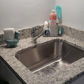 A neatly arranged kitchen sink on a granite countertop.