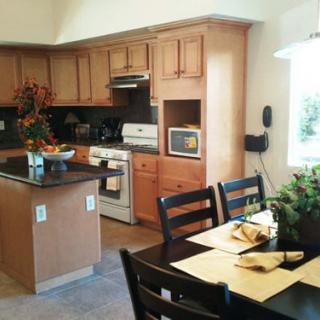 A modern kitchen with wooden cabinets, featuring a dining area and central island.