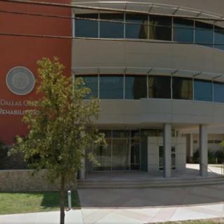 The image shows the exterior of an office building with large windows and a main entrance, accompanied by some trees in the foreground.