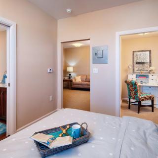 A cozy bedroom with a tray on the bed and view into adjoining rooms.