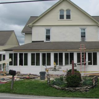 A house undergoing renovation with new windows and construction materials in the yard.