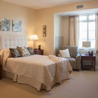 A cozy and elegantly decorated bedroom with a bed, armchair, and window.
