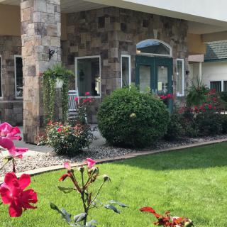 A charming house with a stone facade, surrounded by a well-maintained garden full of colorful flowers and lush greenery.