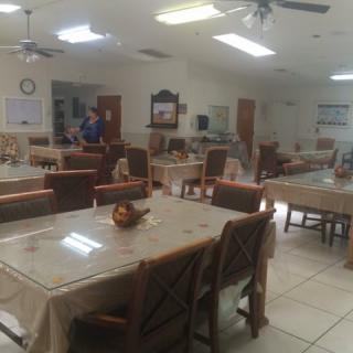 A spacious dining area with multiple tables and chairs, illuminated by fluorescent lights.