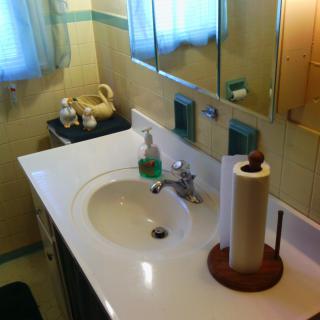 A cozy bathroom with a sink, mirror, and various toiletries arranged neatly.