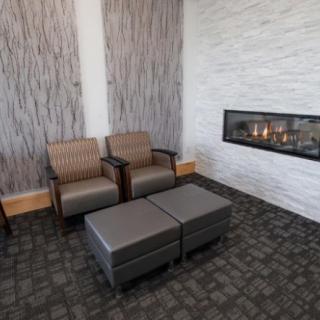 A modern lobby with comfortable chairs and a sleek fireplace.