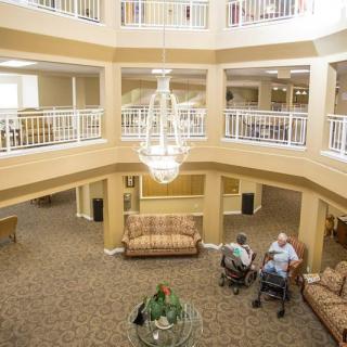 A spacious lobby with a large chandelier, designated seating areas, and people socializing.
