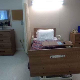 A hospital room with a single bed prepared for patient care.