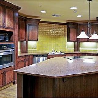A modern kitchen with wooden cabinets, a large island, and stainless steel appliances.