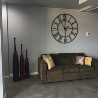A modern living room featuring a comfortable sofa, decorative vases, and a large wall clock.