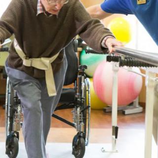 An elderly person receiving physical therapy support for rehabilitation.